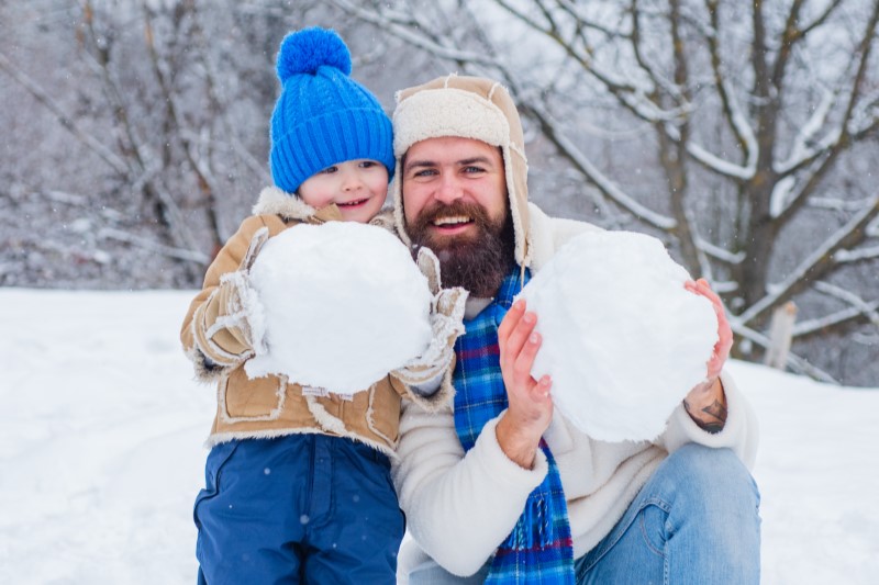 father and son holding snow balls