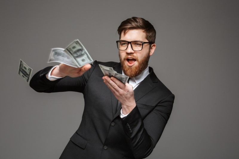 man in suit with beard making it rain with $100 bills